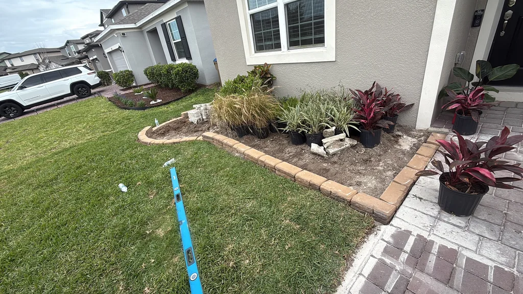 Long curved bed of ornamental grasses and shrubs edged with tan block along a lawn