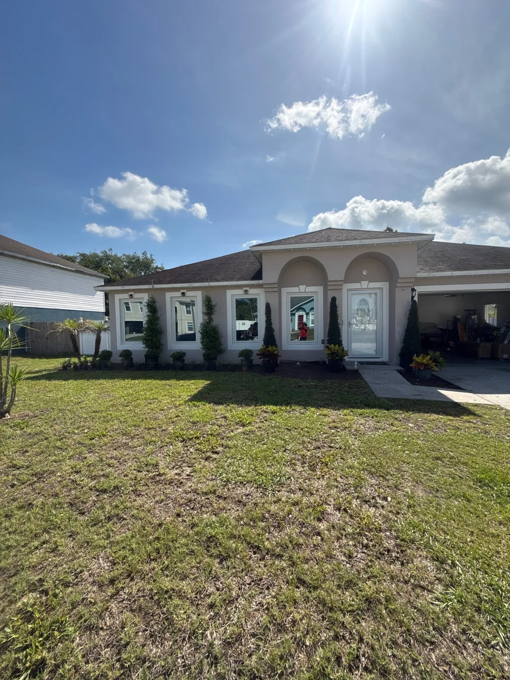 Freshly mowed front lawn before a stucco home with an arched entry and young palms