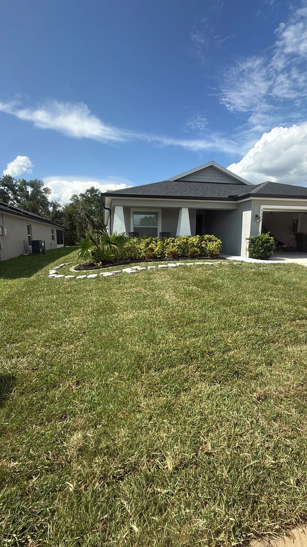 Cut lawn curving around a shrub bed at the front corner of a single story home