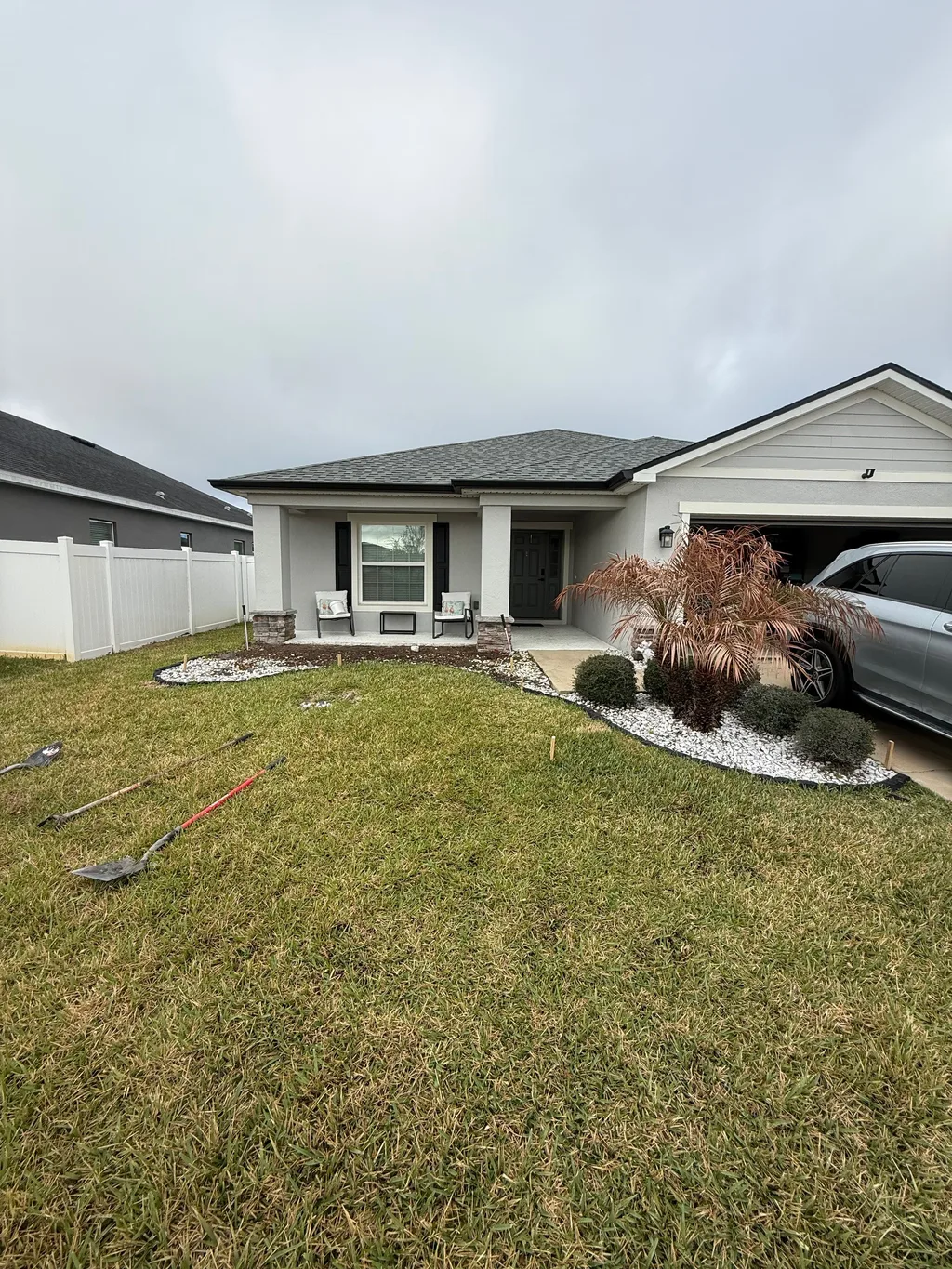 Trimmed front lawn and walkway leading to a two car garage under an overcast sky