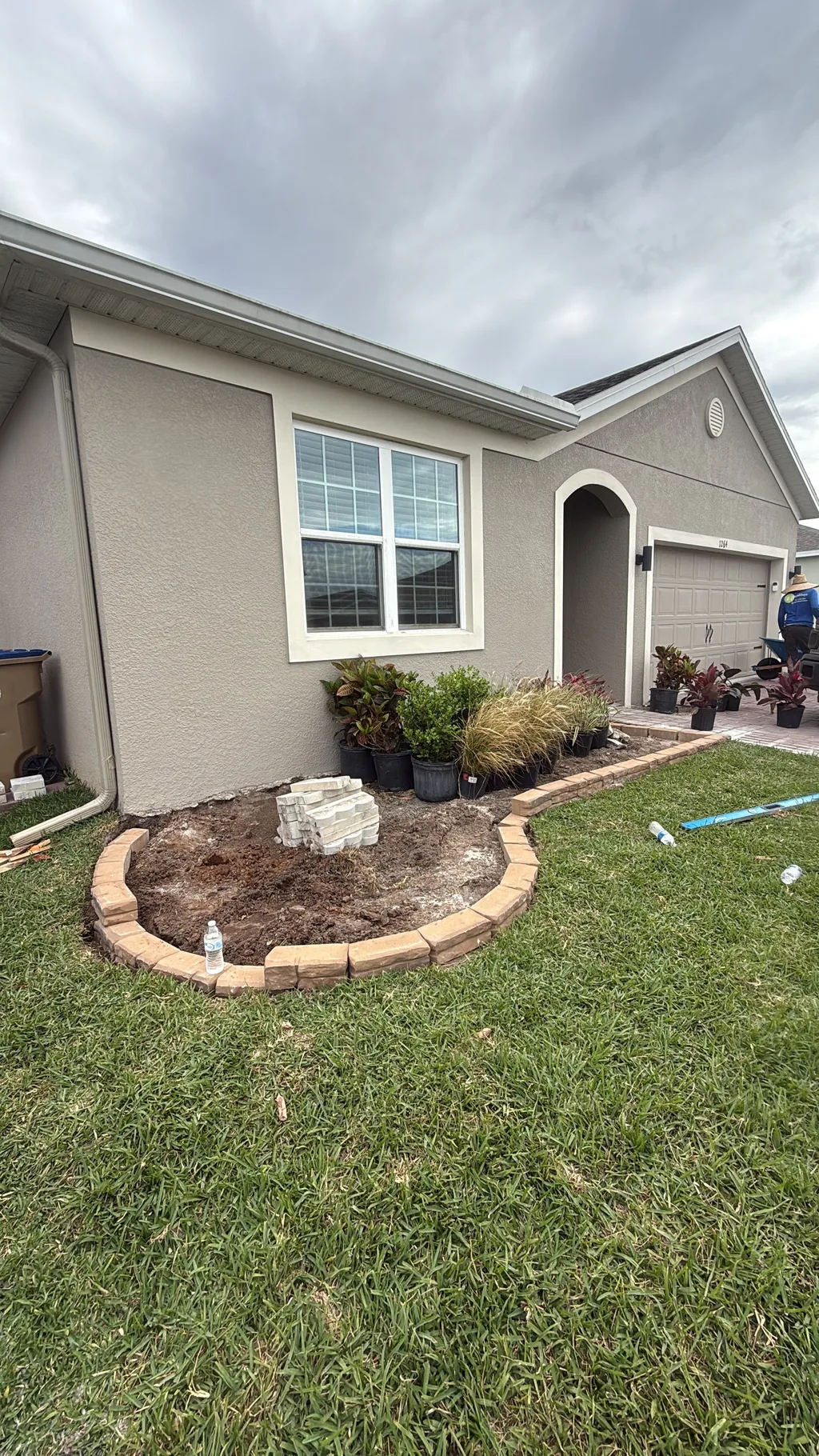Fresh mulch bed edged with a curved tan paver border beside a residential front lawn