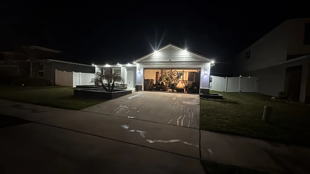 Lit garage and driveway at night with landscape lighting along the front of a home