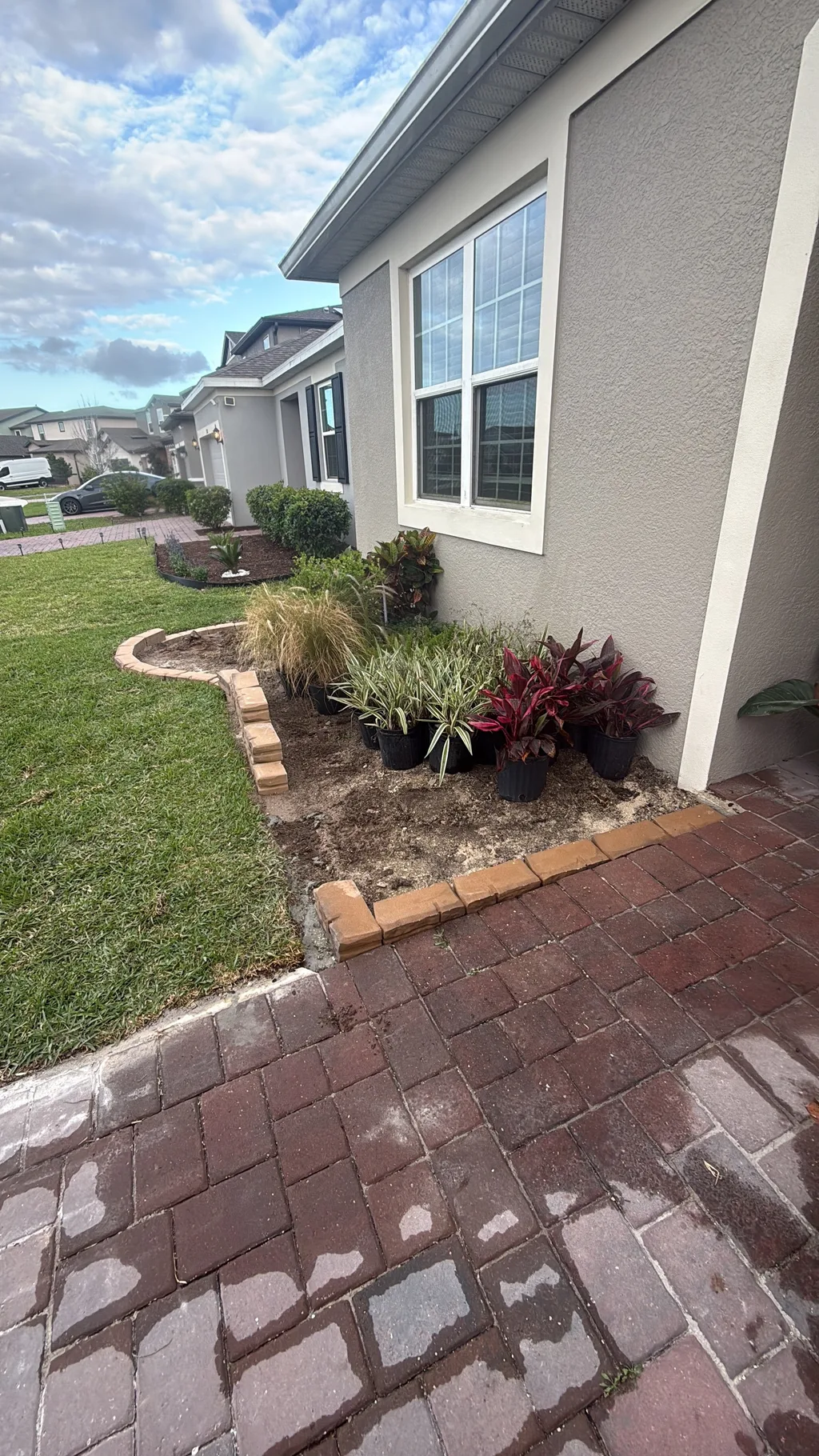 Curved paver border separating a planted mulch bed from the lawn beside a walkway