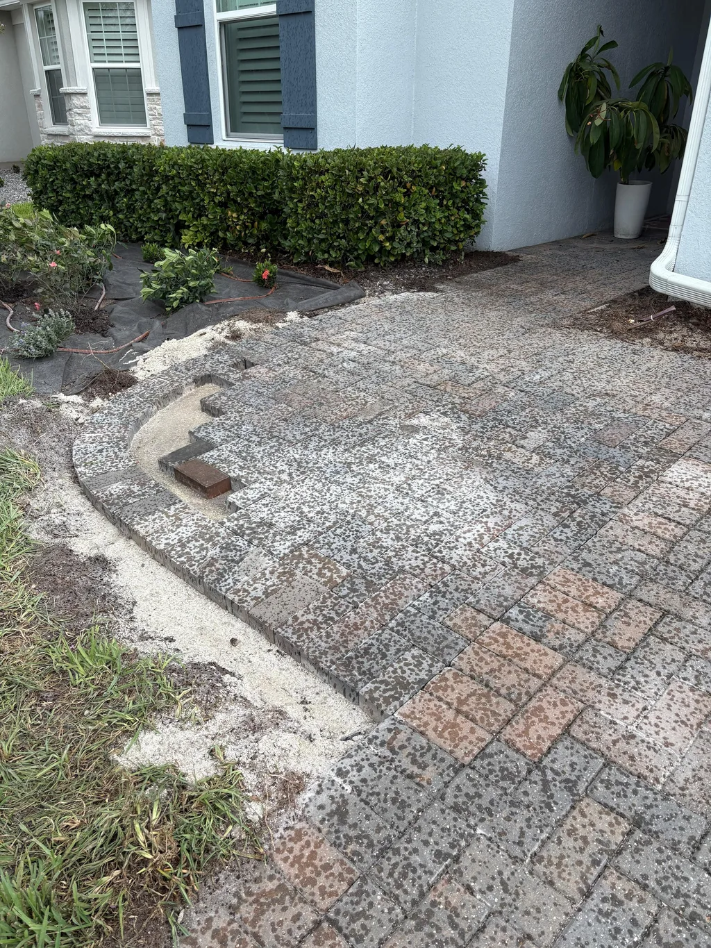 Finished paver surface with a curved edge meeting a compacted base beside a wall