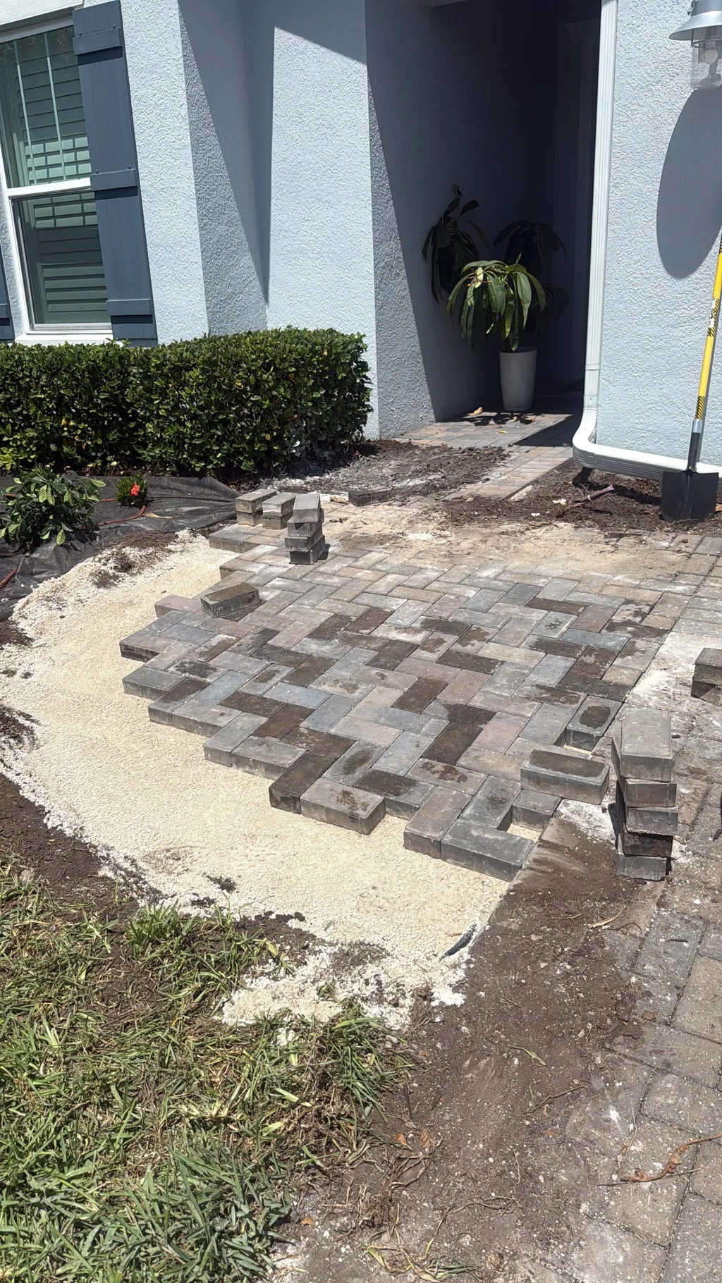 Interlocking pavers partly laid across a leveled base with stacks waiting to be set