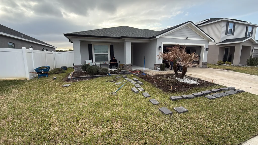 Square concrete pavers set as a stepping path across a front lawn to a driveway