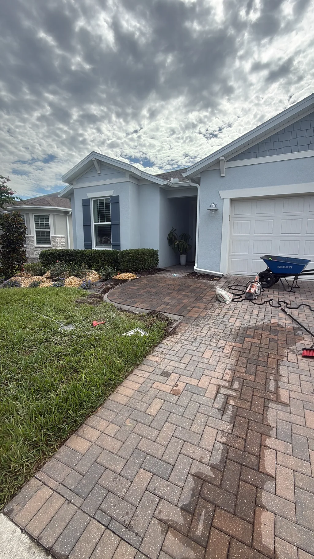 Paver walkway bordered by a planted mulch bed leading to the entry of a stucco home